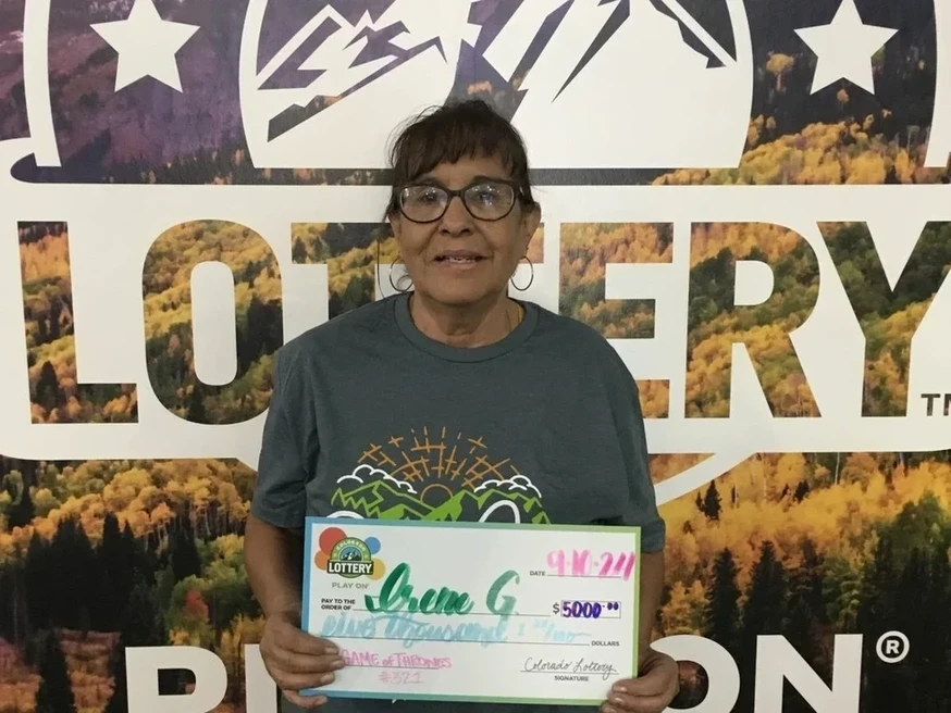 Irene G. 手持一张 5,000美元的大支票，在科罗拉多彩票的背景前